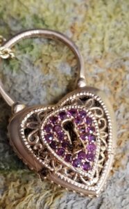 A dirty gold locket with pink stones